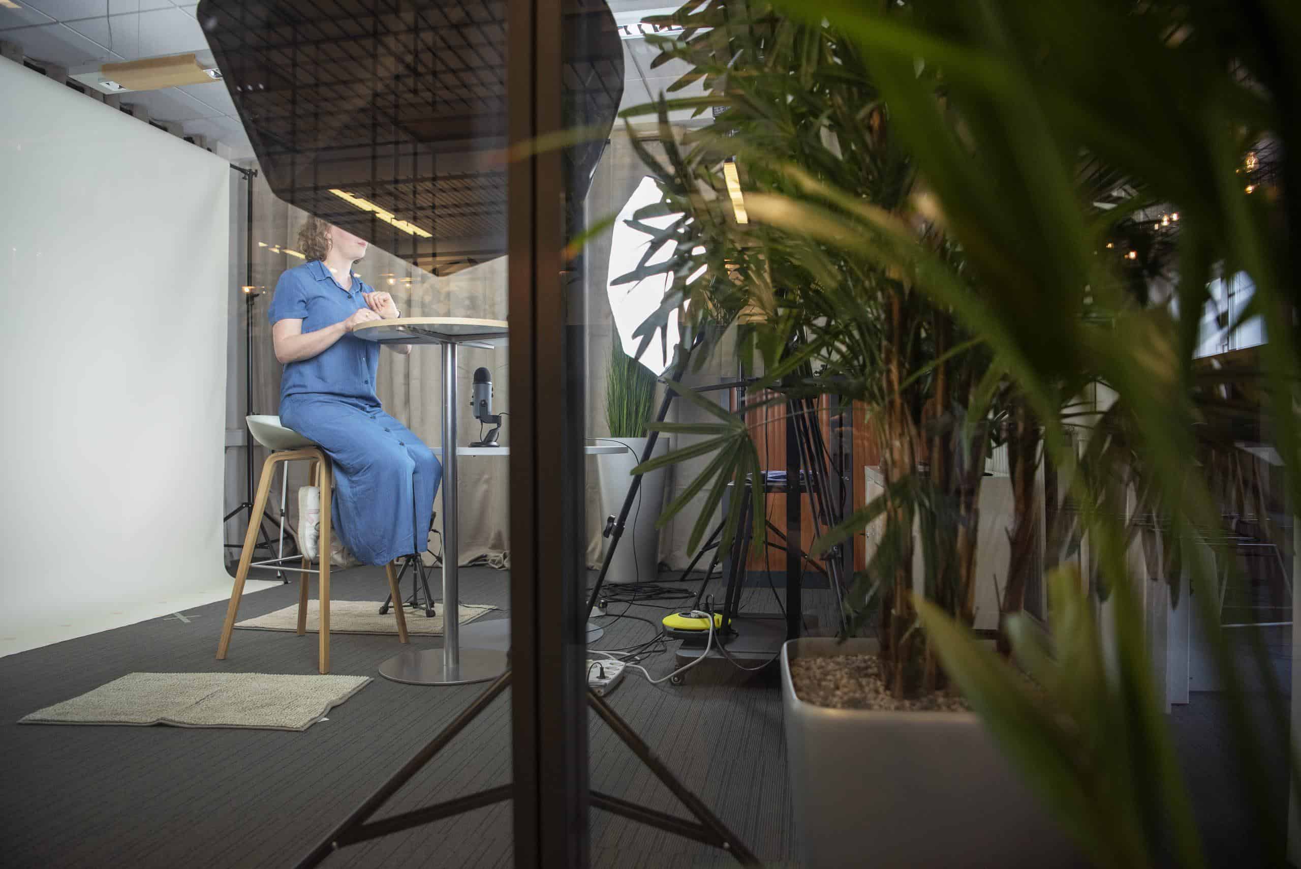 Medewerker zit in een opnamestudio en neemt een screencast op.